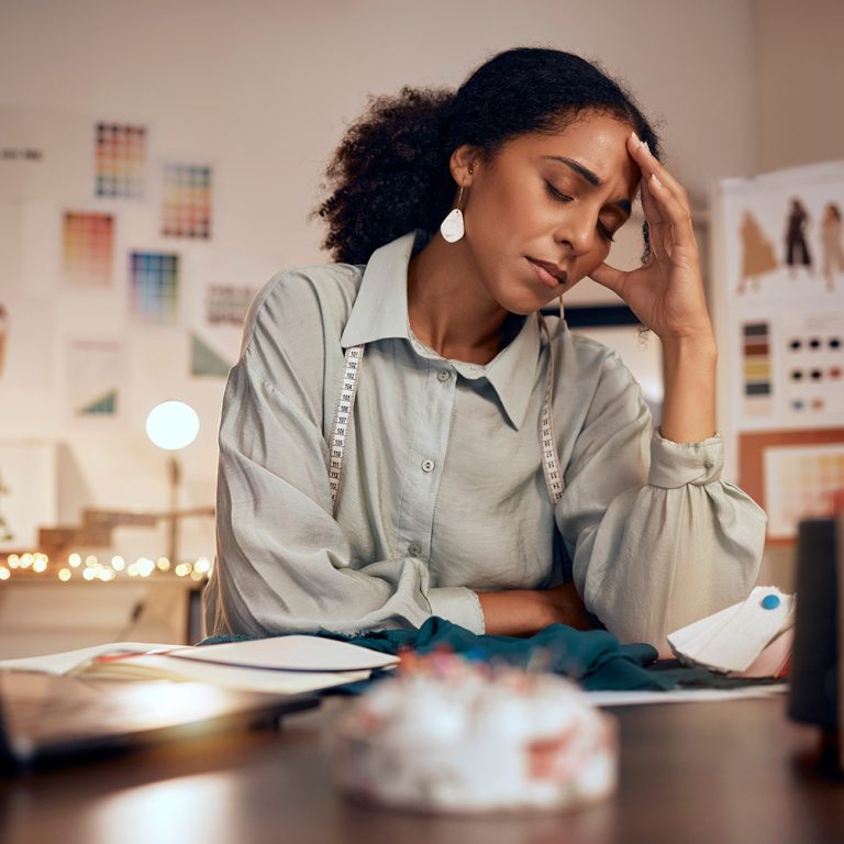 Stress, headache and fashion, woman designer in studio with laptop, burnout and financial anxiety. .