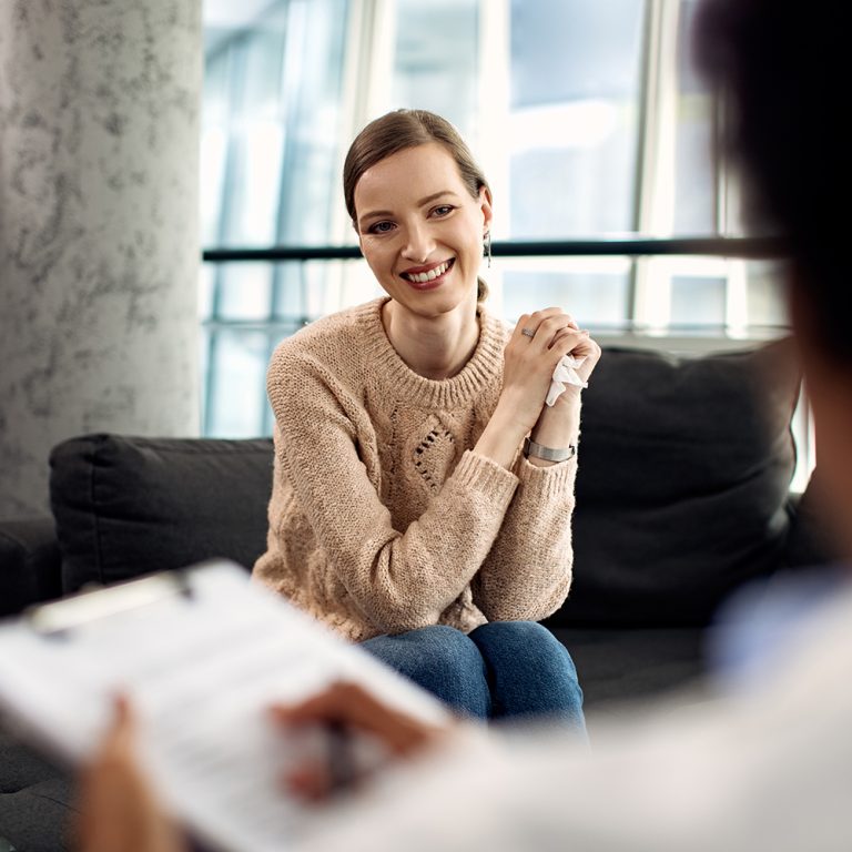 Young happy woman communicating with psychologist during therapeutic session.