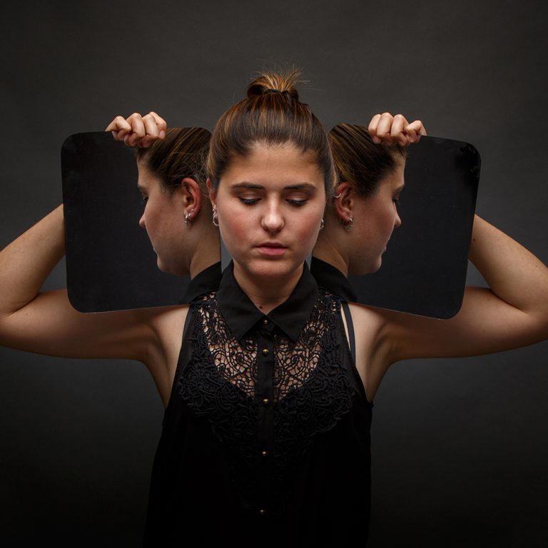Modern model holding mirrors on sides of face